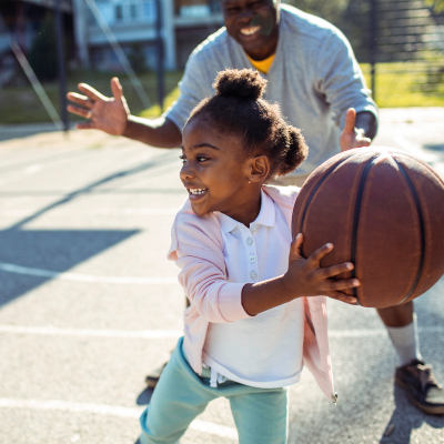 A father and his daughter playing basketball on a court at Prospect View in Santee, California