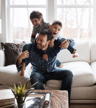 Young boys climbing on their dad in the living room at Hollybrook Farms Apartments in Laurel, Delaware