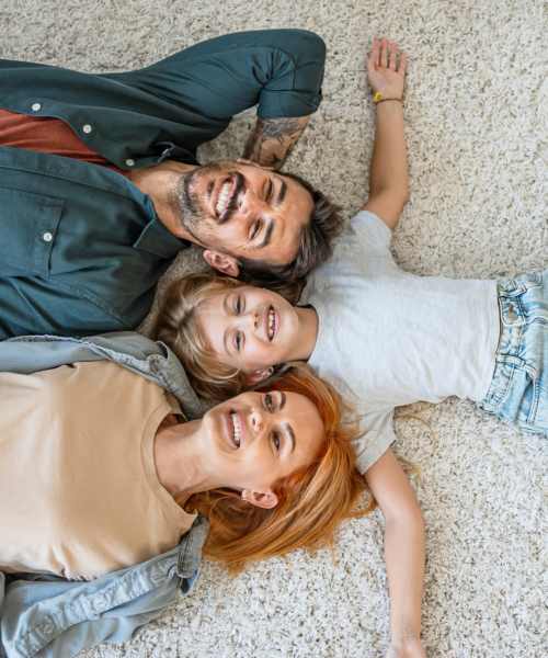 Family relaxing on the carpeted floors at Broadway West in Brentwood, New York