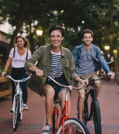 Smiling woman riding a red bicycle near Brush Factory Lofts in Philadelphia, Pennsylvania