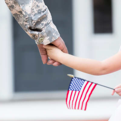 A military member holding hands with a child at Liberty Military Housing in Newport Beach, California