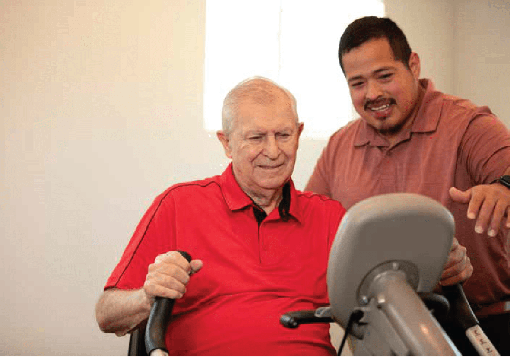 Resident and caregiver using an exercise machine at Clearwater at The Arboretum in Austin, Texas