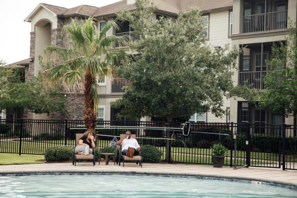 Two people laughing poolside at Belmere Luxury Apartments in Houma, LA together.