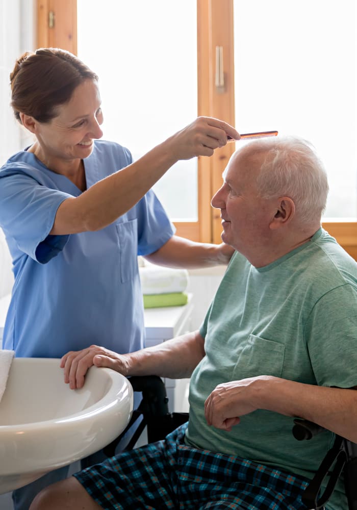 A nurse at Eagle Lake Village Senior Living in Susanville, California helps a resident comb his hair