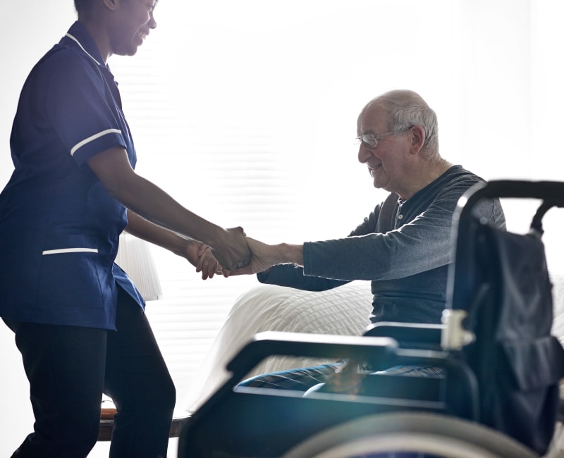 A caregiver helping a resident to his bed at The Sanctuary at Brooklyn Center in Brooklyn Center, Minnesota