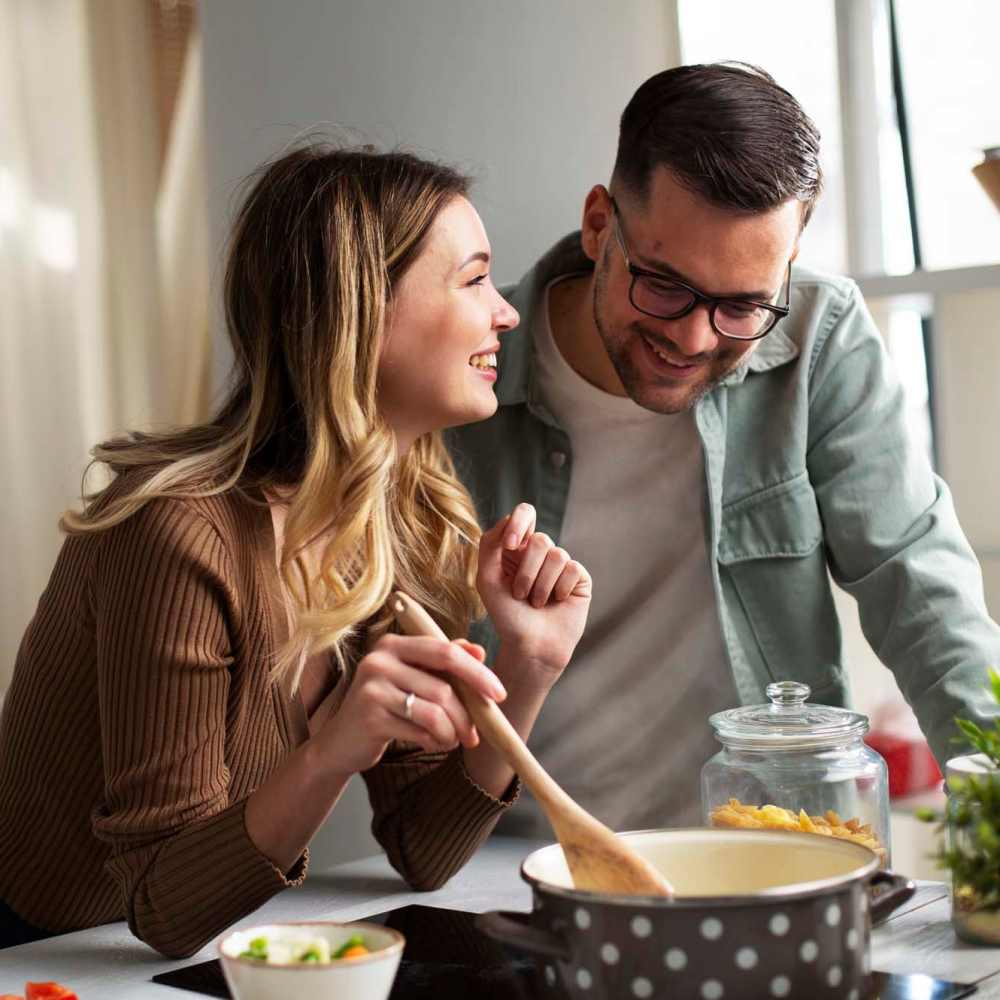 Couple preparing a dish in their kitchen at Village Apartments in Bellaire, Michigan