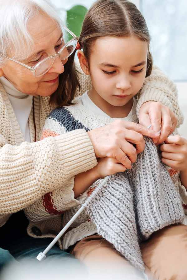 Resident showing a young girl how to knit at Merrill Gardens at Sherwood in Sherwood, Oregon