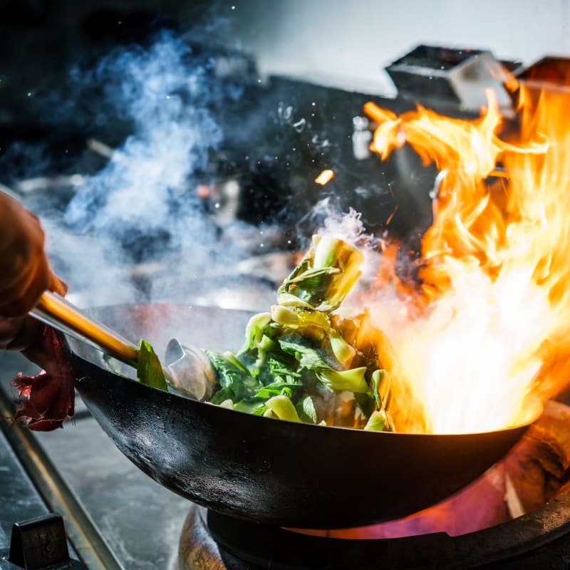 Chef cooking fresh vegetables in a wok at one of the seaside restaurants at Portside Ventura Harbor in Ventura, California