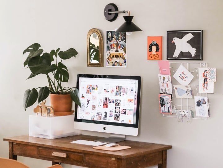 an organized and personalized desk space, with photos on the wall, a plant on the desk and computer