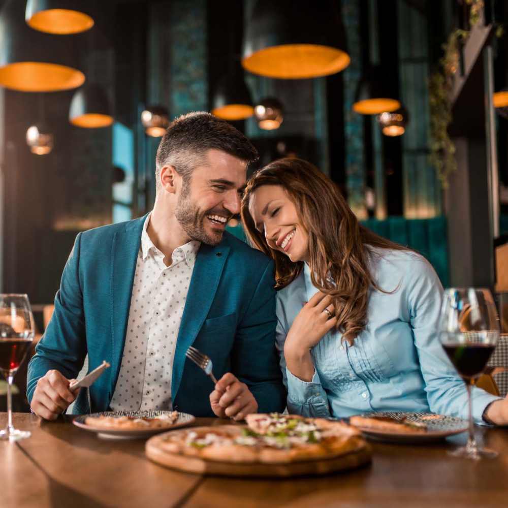 Resident couple sharing a laugh over a meal at their favorite restaurant near Oak Ridge Apartments in San Antonio, Texas