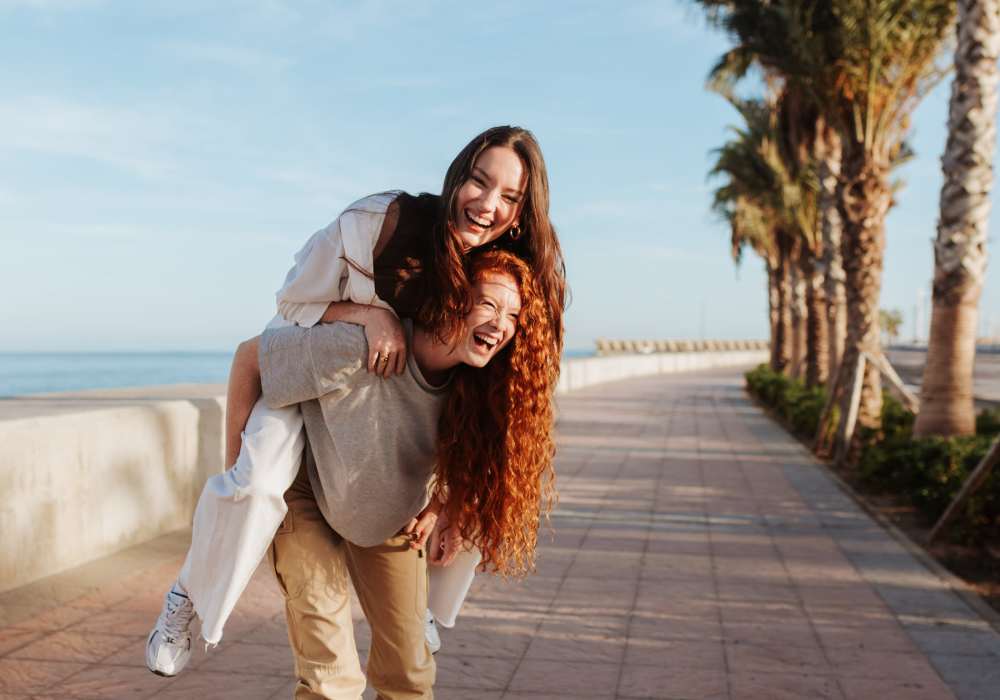 Friends smiling while one carries the other on her back outside near The Southerly at Orange City in Orange City, Florida