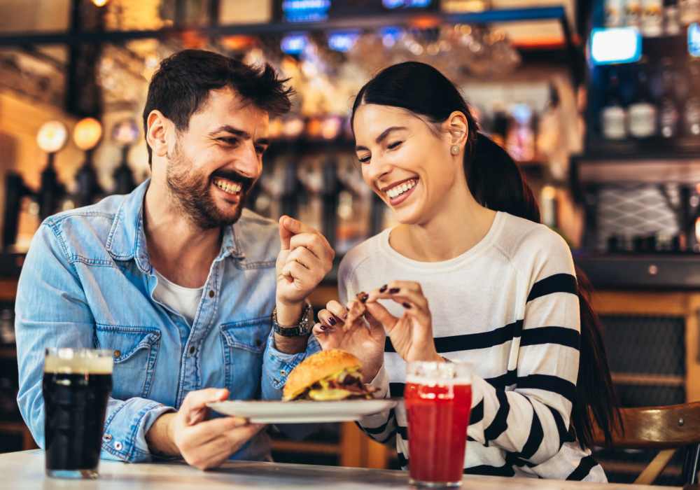 A couple sharing a meal and drinks in a restaurant near Ascent Apartment Homes in Asheville, North Carolina