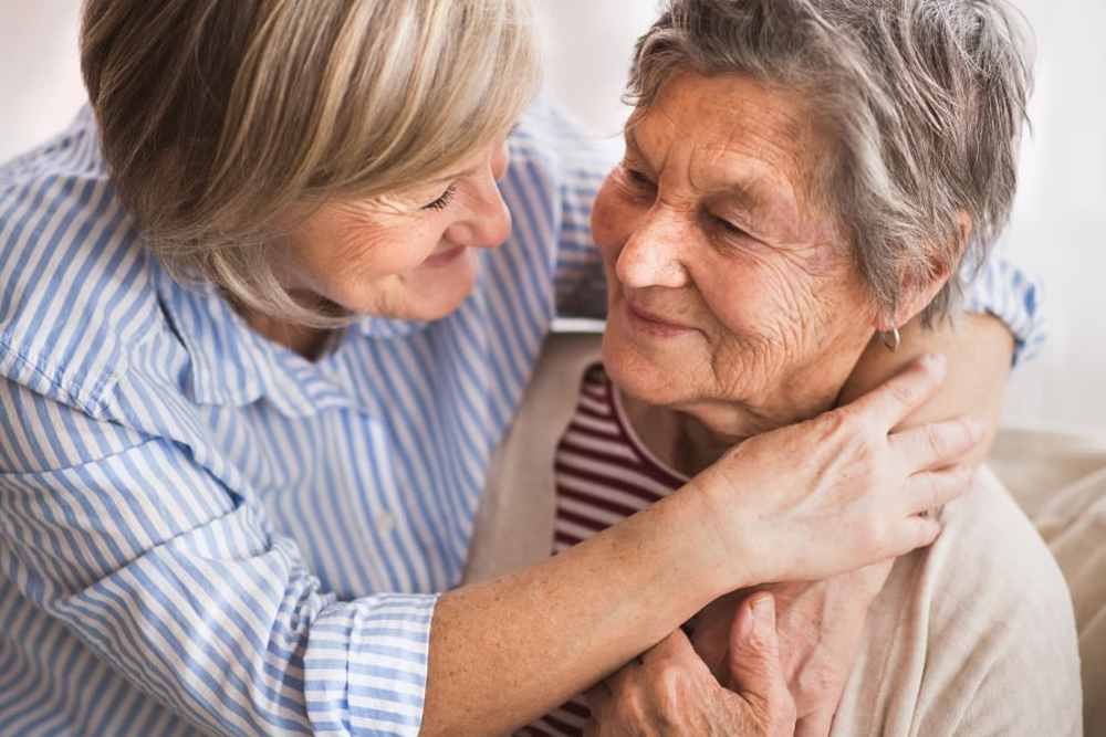 Caregiver hugging memory care resident  at Vista Prairie at Windmill Ponds in Alexandria, Minnesota