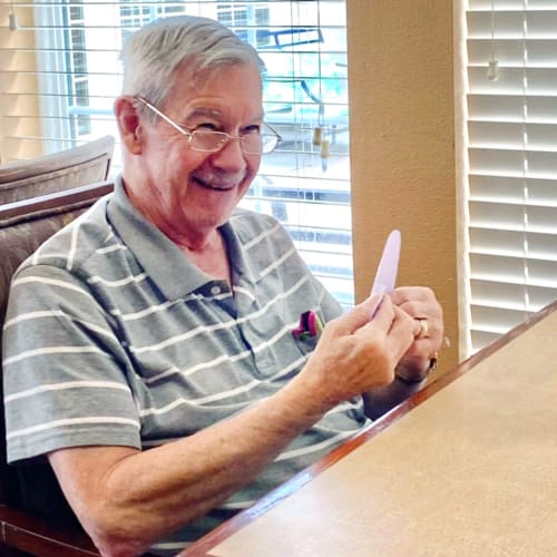 Smiling resident crafting at Oxford Glen Memory Care at Sachse in Sachse, Texas