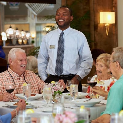 Residents and staff member talking in the dining room at AgeWell Living