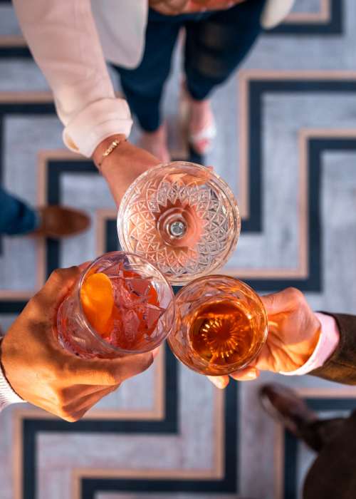 Friends toasting with fancy looking drinks near Broadway Apartments in Richmond, Virginia