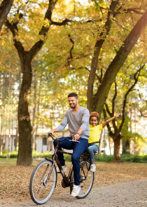 A father riding a bike through a park with his child near Covington Park in Jackson, Mississippi