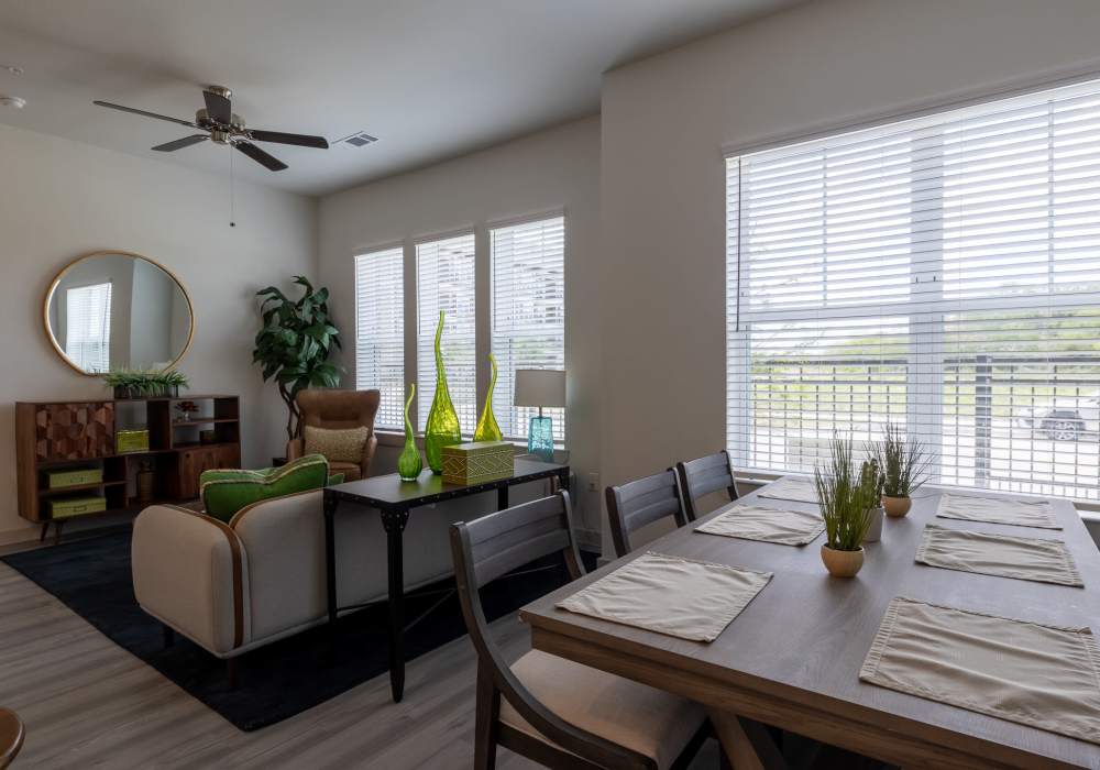 Bright apartment dining and living area featuring a rectangular dining table with place settings at Charleston at Fannin Station in Houston, Texas