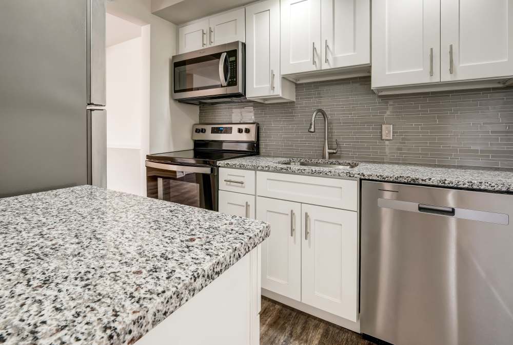 Modern kitchen with white cabinets, granite countertops, and stainless steel appliances at Imperial North Apartments home in Rochester, New York