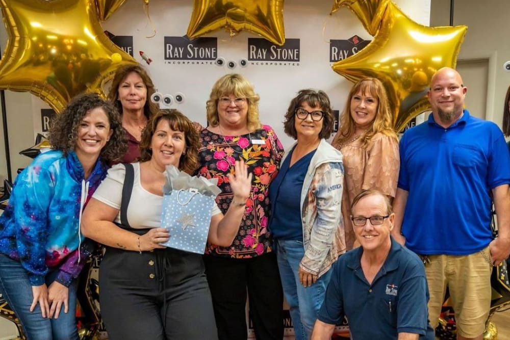 A team picture with large gold star balloons at Ray Stone Inc.