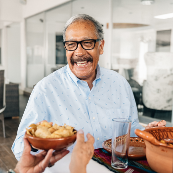 Resident smiling while his wife passes him a bowl of food