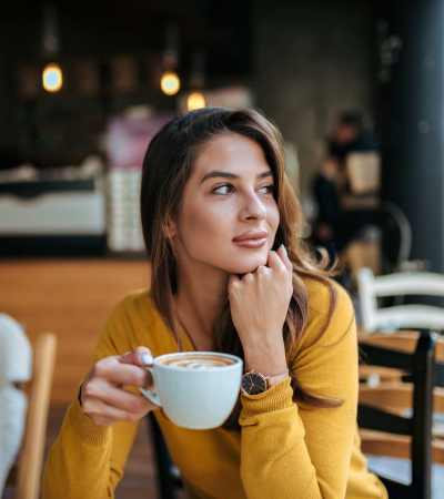 A woman smiling as she drinks coffee near Brentwood Apartments in Portland, Oregon