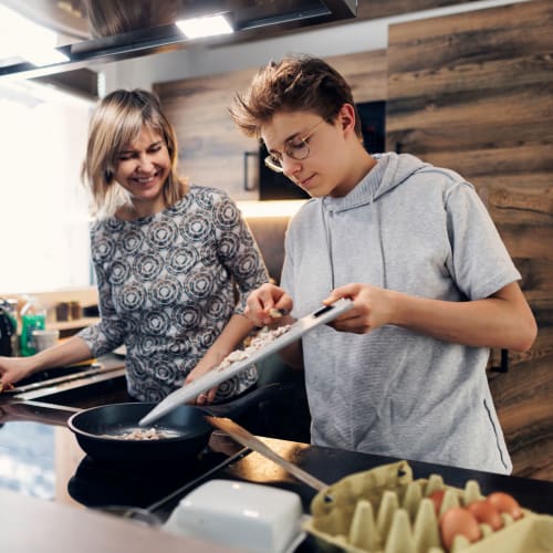 A parent and teenage child cooking in their kitchen at Union SLU in Seattle, Washington