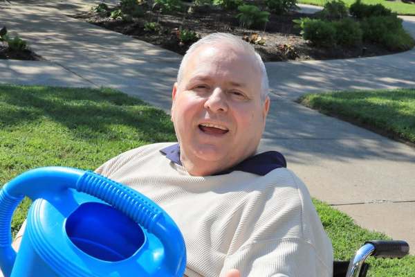 resident in a wheel chair outside in the garden with a watering can Chesterfield, Chesterfield in MO