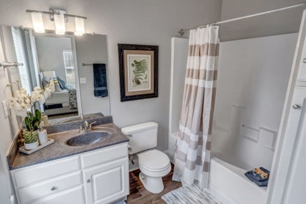 An apartment bathroom with a tub and cabinet storage at Brighton Park in Byron, Georgia