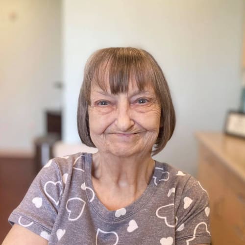 A seated resident smiling at Oxford Glen Memory Care at Carrollton in Carrollton, Texas