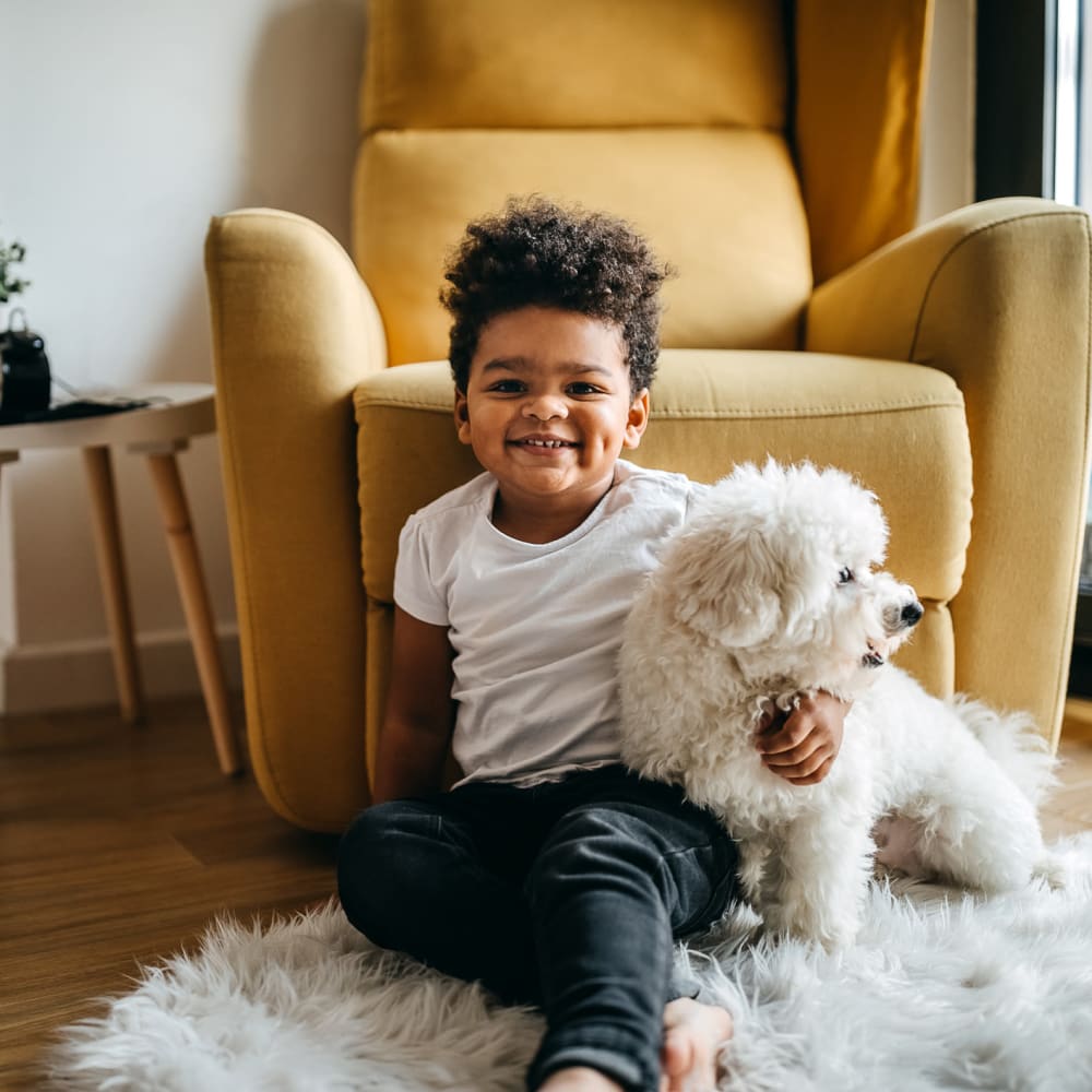 Happy child and his puppy relaxing on the floor in their new apartment's living area at Mission Rock at San Rafael in San Rafael, California