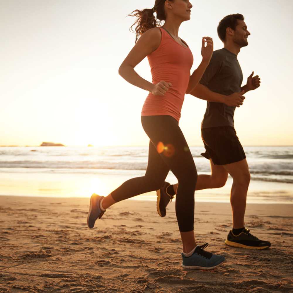 Young man and woman jogging along the beach at Taft Terrace in Taft, Texas