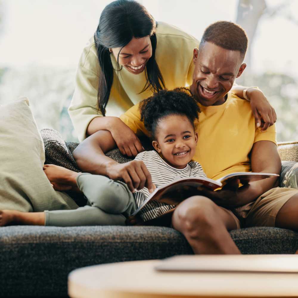 Family relaxing on a couch by reading book at Covey Run Apartments in Forest Grove, Oregon