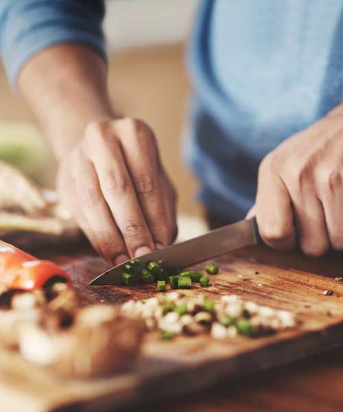 Resident chopping fresh vegetables in the sleek, modern kitchen at Firwood Station in Portland, Oregon