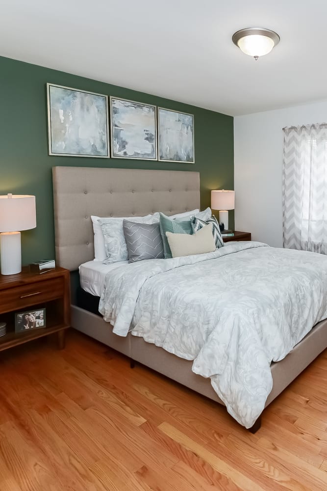 Model bedroom with a green accent wall at Elmwood Village Apartments & Townhomes in Elmwood Park, New Jersey