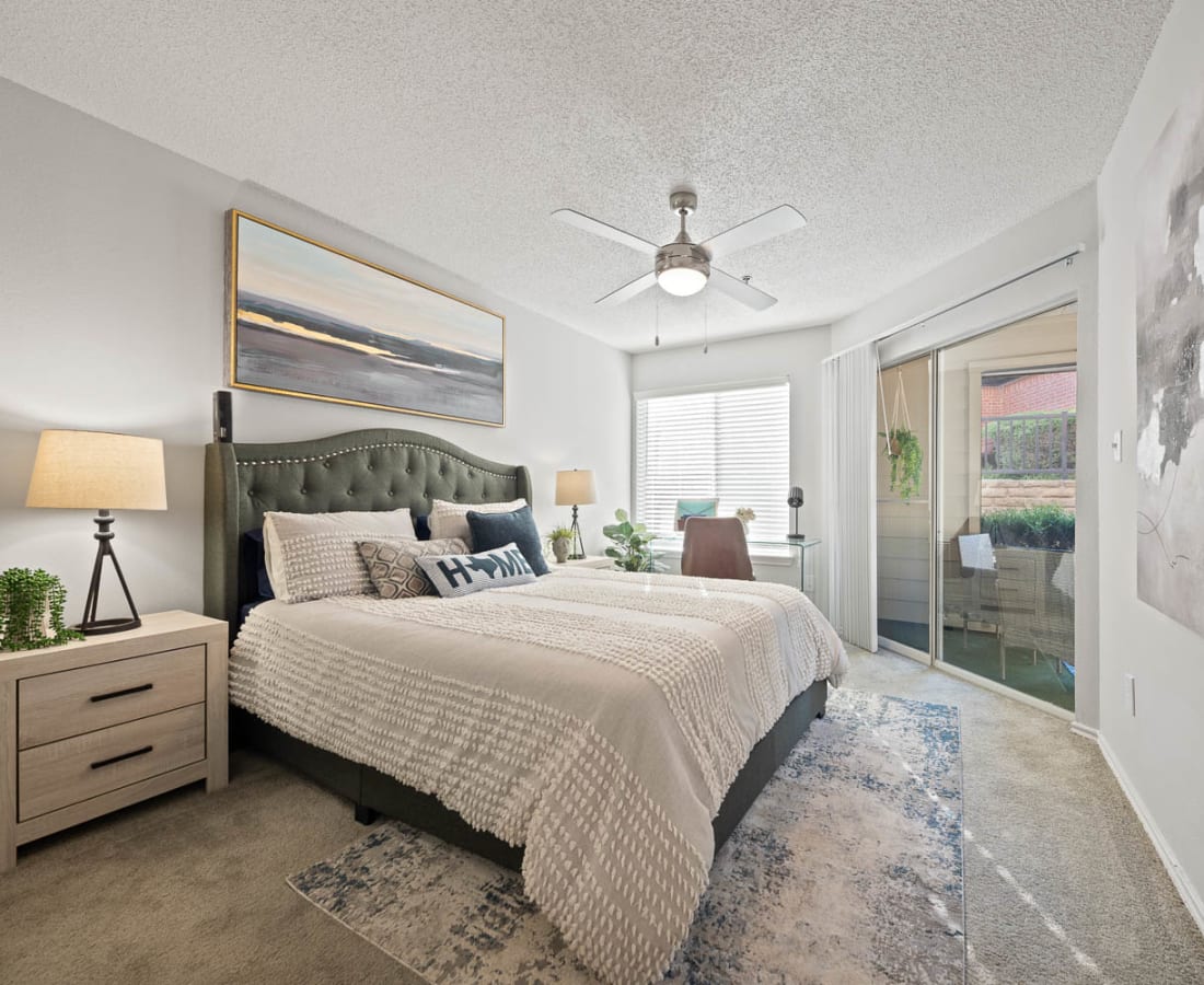 Model bedroom with plush carpet and a ceiling fan at Somerset in Lewisville, Texas
