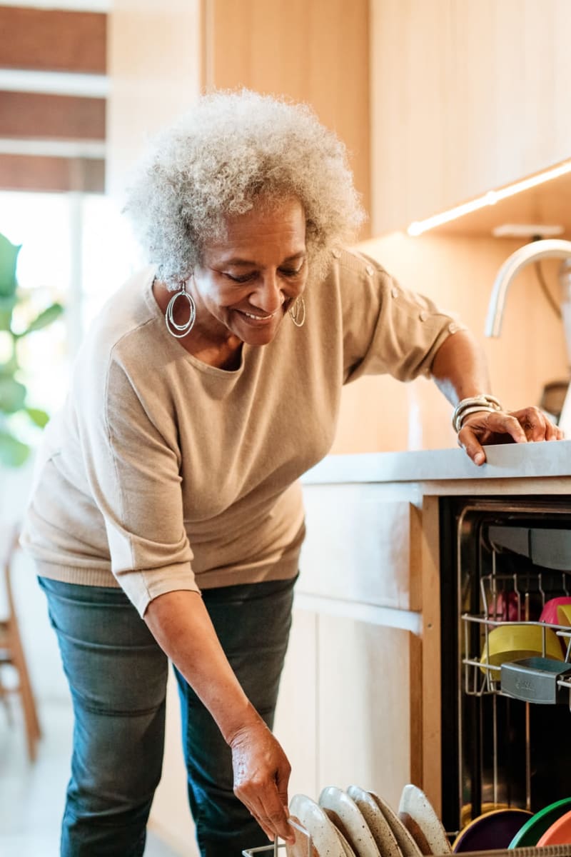 Resident emptying the dishwasher in their home at Transitions At Home - West in Mount Horeb, Wisconsin