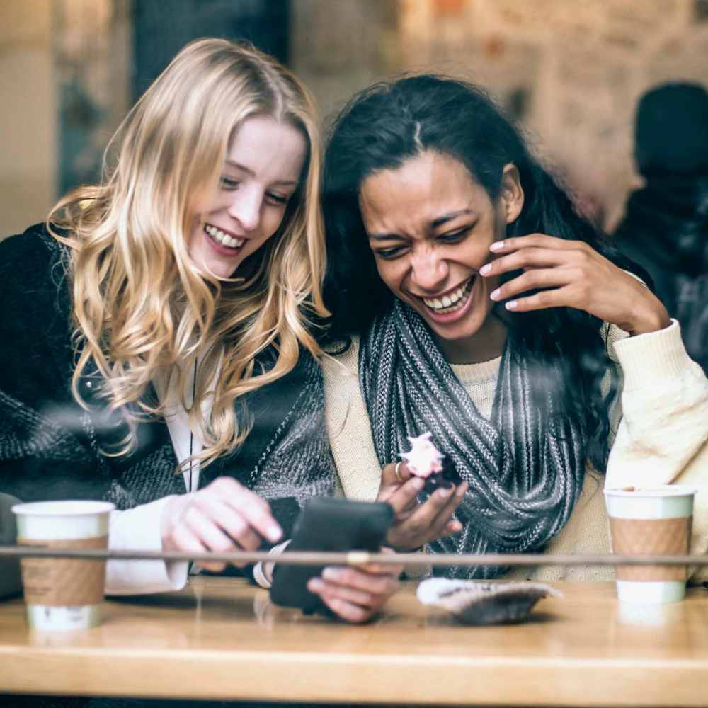 Resident friends sharing a laugh over a meal at their favorite restaurant near Tucasa Townhomes in Irving, Texas