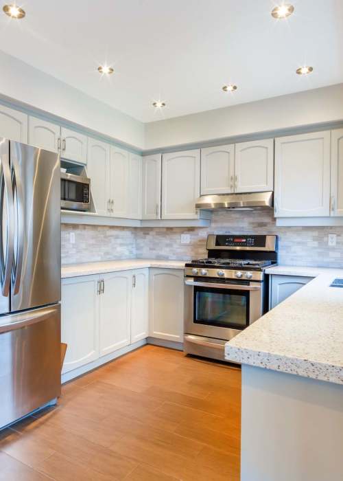Kitchen with refrigerator, microwave and modern lighting at Avalon in Davis, California