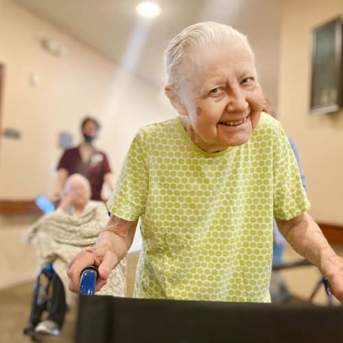 Resident walking and smiling at Oxford Glen Memory Care at Carrollton in Carrollton, Texas
