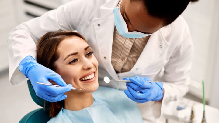 a female dentist inspecting a woman’s teeth with dental tools | dental clinics in Casper