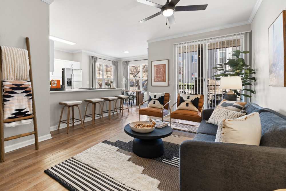 Living room with couch, accent chairs, barstools along the kitchen counter, and sliding door going out to the patio.