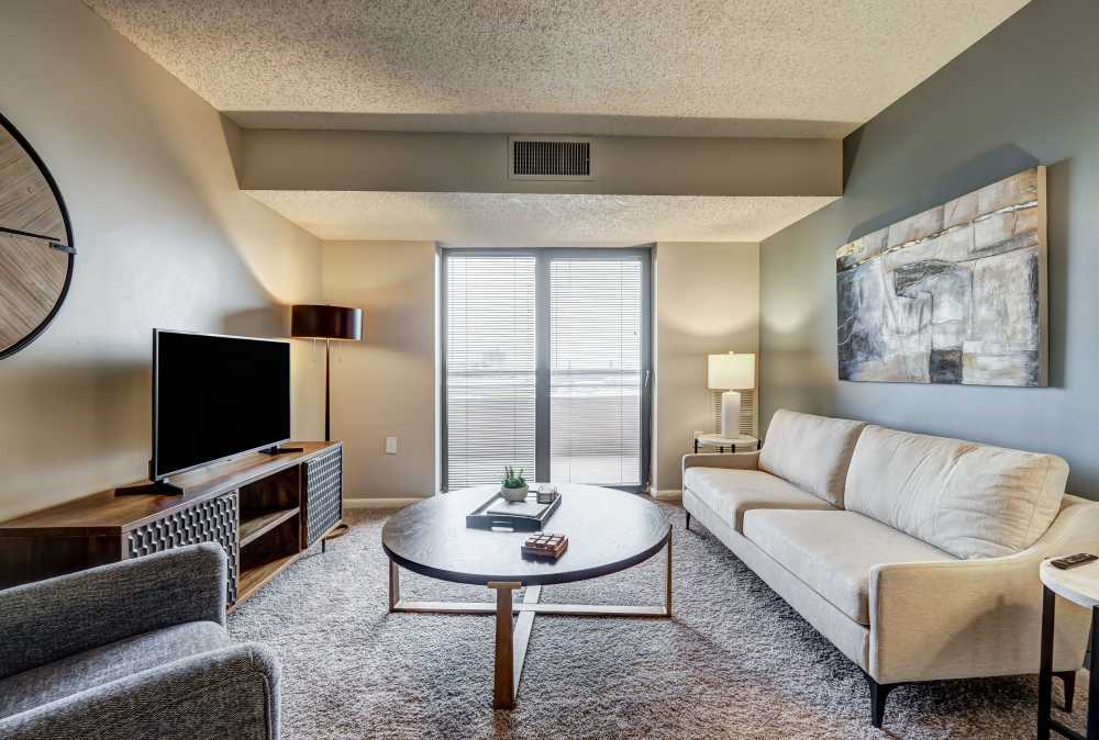 Living room with carpet leading to a private balcony at River Park Tower Apartment Homes in Newport News, Virginia
