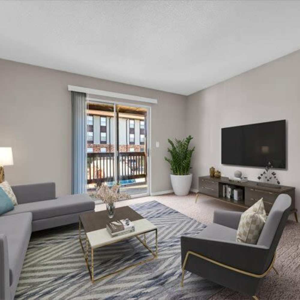 Bright living room with cozy seating, large windows at Woodbrook in Gardendale, Alabama