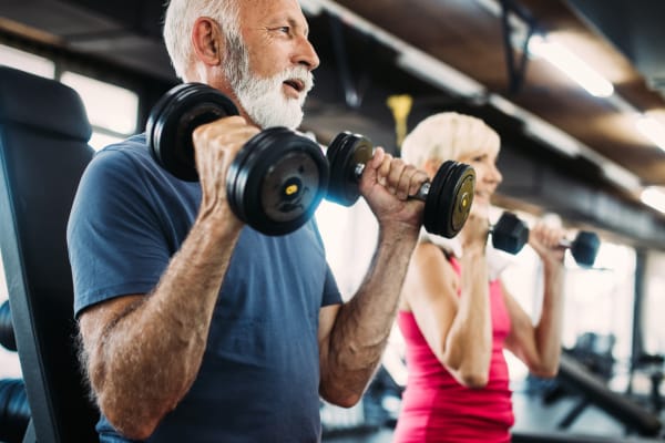 Older couple doing a barbell work  out in a fitness center