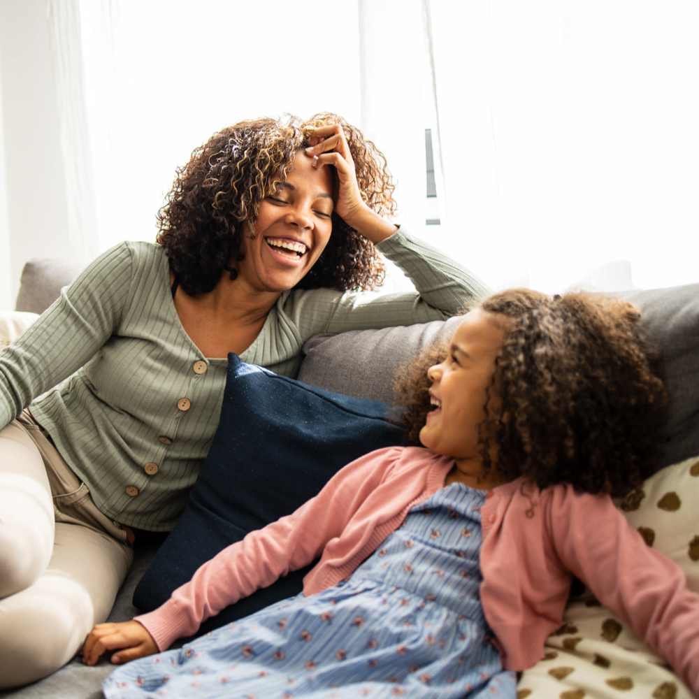Resident and her kid sitting on the couch, in the living room at East Bend Trace in Greenville, North Carolina