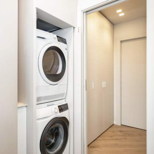 A stacked washer and dryer in a laundry room at Cavalier Greene in Corunna, Michigan