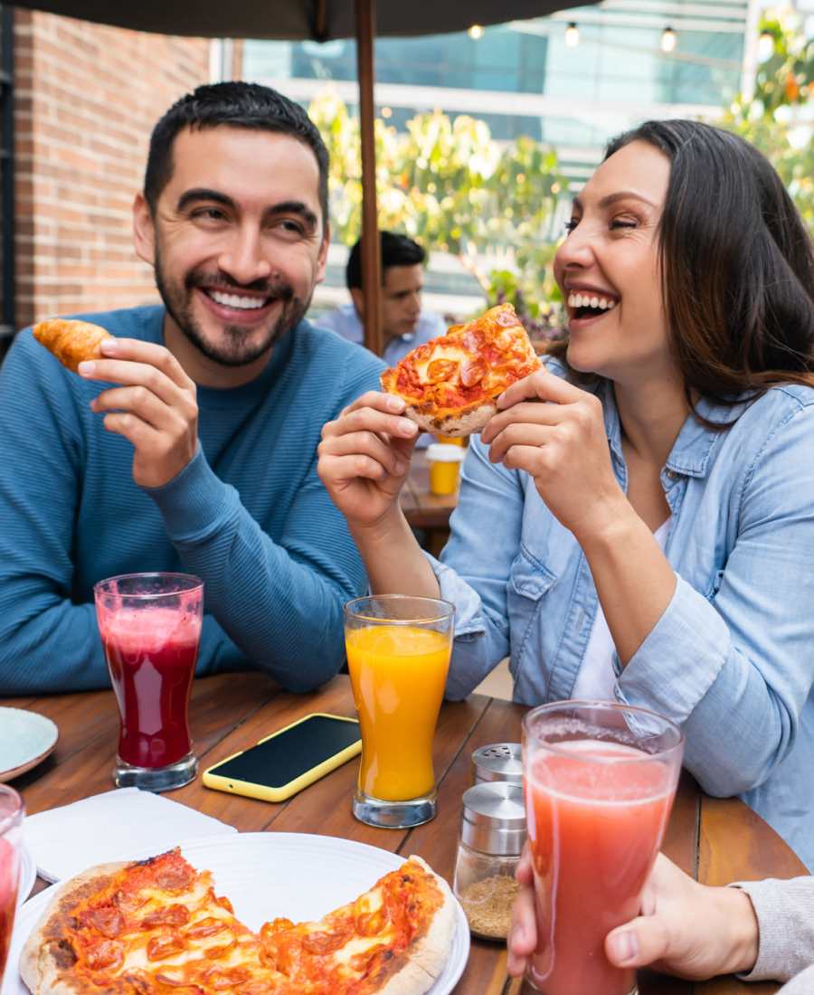 Friends smiling as they eat pizza in the neighborhood of Waters Edge in Sacramento, California