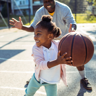 A resident and child playing basketball on a court at Bellevue in Washington, District of Columbia