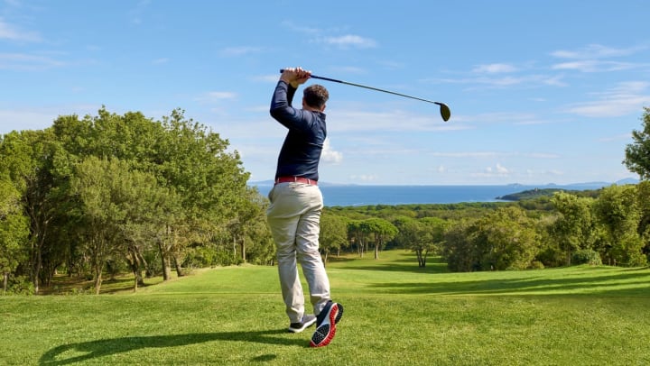 A golfer finishing a swing on a beautiful course